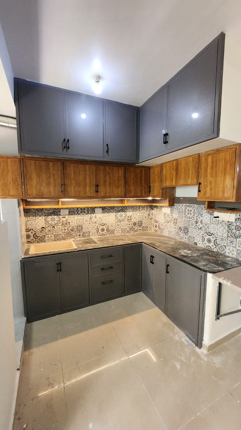 Grey and wood-tone PVC/uPVC modular kitchen with a patterned tile backsplash and under-cabinet lighting